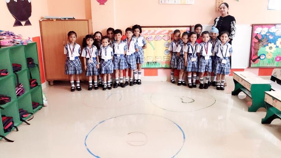 Joyland children standing together on a circle marked on the classroom floor, ready for the morning routine