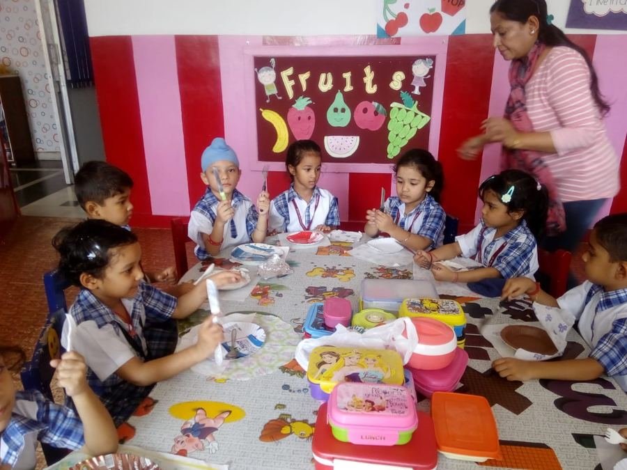Joyland children and their teacher sharing a meal at a decorated classroom table