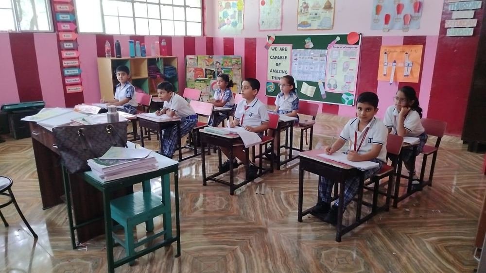 Joyland Montessori School children working at their desks in a bright pink classroom beneath a board reading We are capable of amazing things