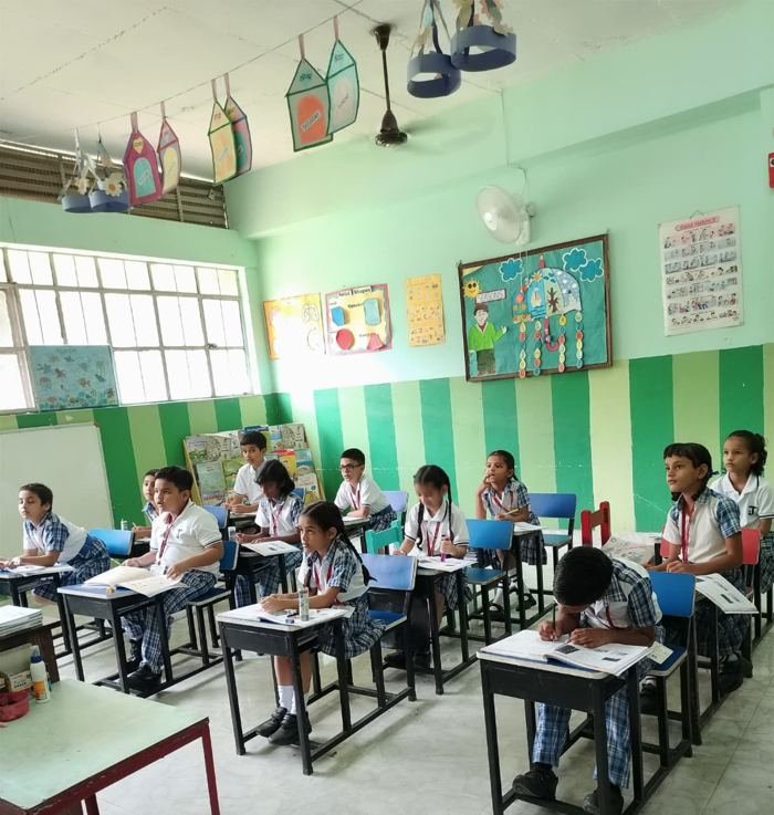 Joyland Montessori School children working at their desks with workbooks in a green-striped classroom