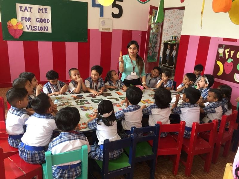 Children and teachers seated together around tables in a Joyland classroom