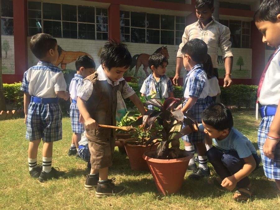 Joyland children and a teacher repotting a plant outdoors