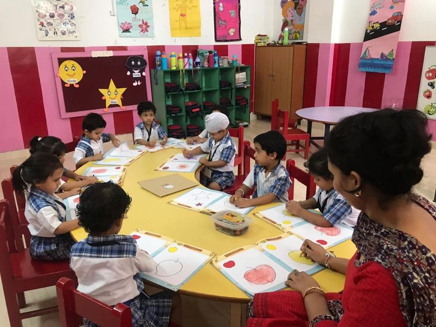 A Joyland teacher sitting with a group of children at a table