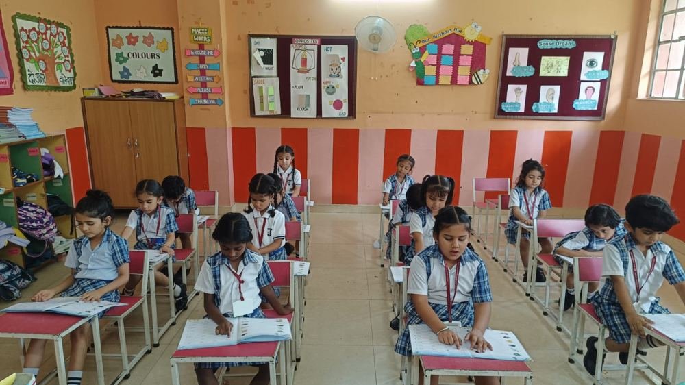 Joyland Montessori School children reading and writing at their desks in an orange-striped classroom