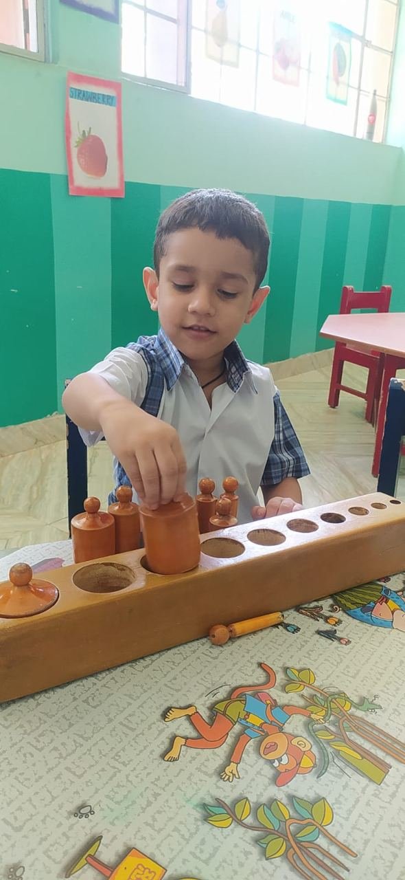 A Joyland child carefully working with a wooden practical-life activity