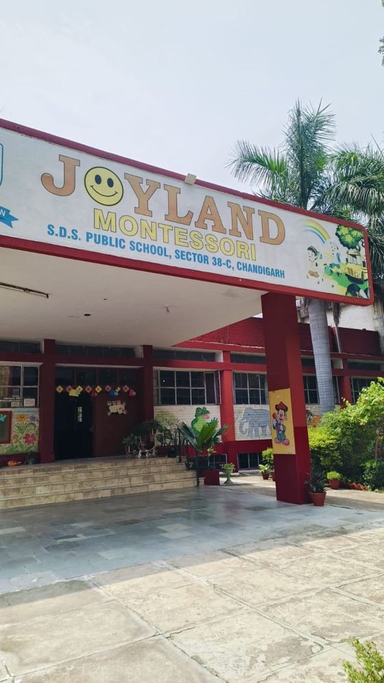 The entrance of Joyland Montessori School with its painted sign, rainbow artwork and red pillars