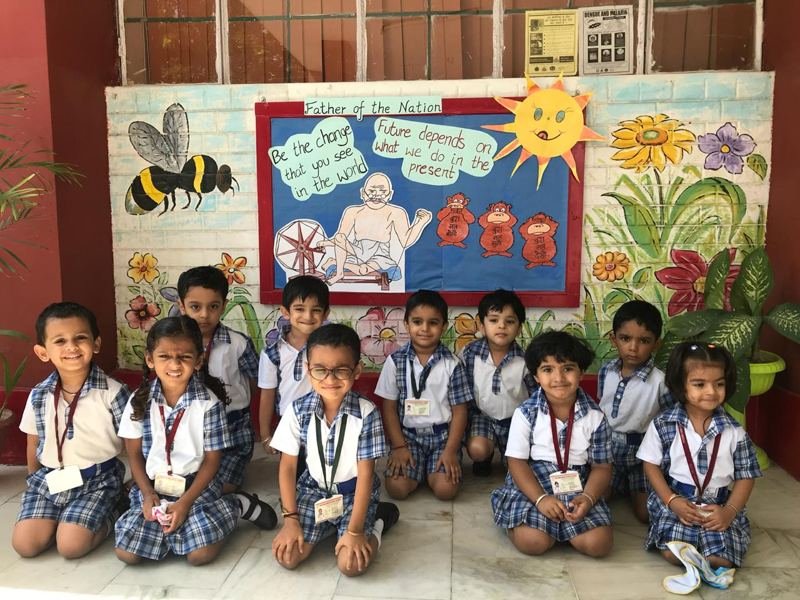 Joyland children seated together on a classroom floor in front of a bee-themed display