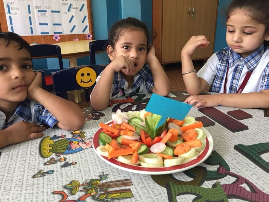 Children enjoying a colourful fruit and vegetable platter at snack time