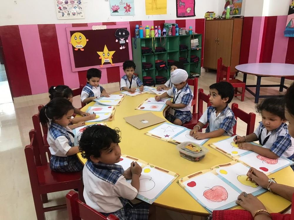 Joyland children working at a yellow table with paper and materials