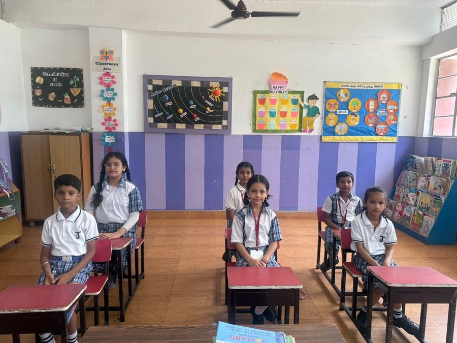 Six Joyland Montessori School children sitting attentively at their desks in a purple-striped classroom